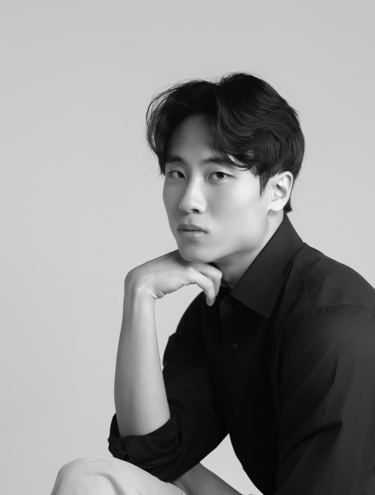The founder of SuhonLabs, seated with one hand resting against his chin, in a black shirt against a plain backdrop.